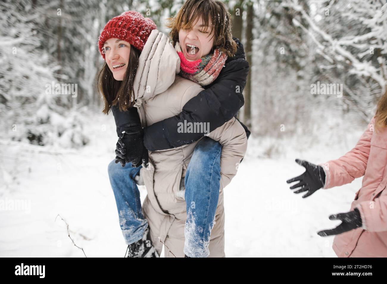 Lustige Teenager-Schwestern und ihre Mutter haben Spaß bei einem Spaziergang durch schneebedeckten Kiefernwald an einem kalten Wintertag. Teenager-Mädchen erkunden die Natur. Winter-Akti Stockfoto