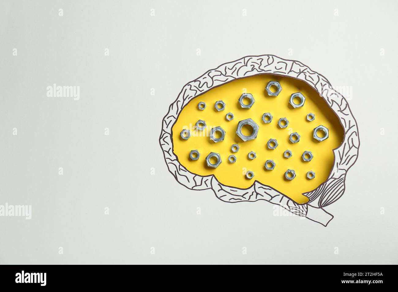 Analytisches Denken. Muttern auf gelbem Hintergrund, Draufsicht durch Papier mit hirnförmigem Loch und Zeichnung. Leerzeichen für Text Stockfoto
