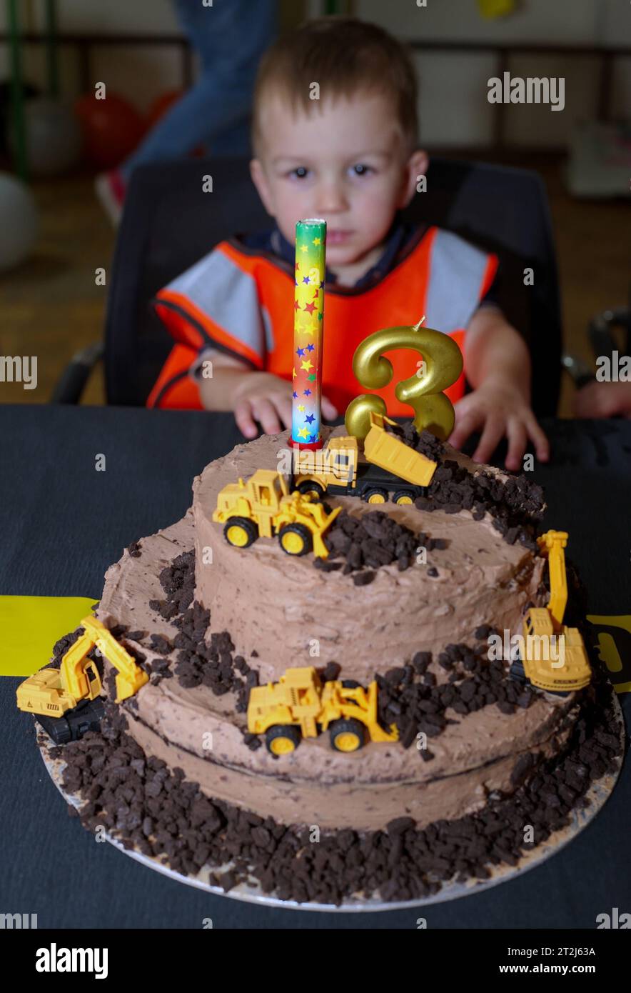 Kleines Kleinkind, das am Tisch vor seiner Geburtstagskuche sitzt Stockfoto