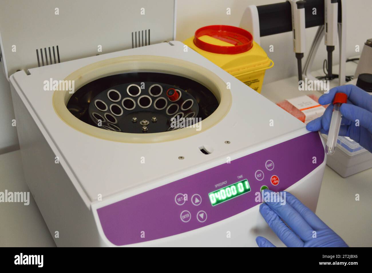 Wissenschaftler, der das Reagenzglas in die Zentrifuge setzt. Stockfoto