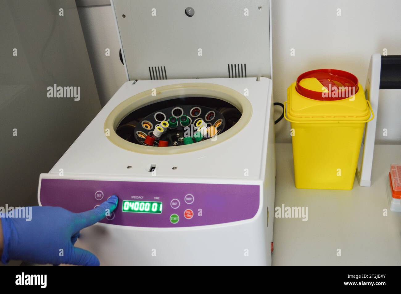 Die Röhrchen werden zum Zentrifugieren in den Analysator gelegt. Durchführung von Labortests. Der Arzt legt das Reagenzglas an und wählt den Modus am Gerät aus. VE Stockfoto