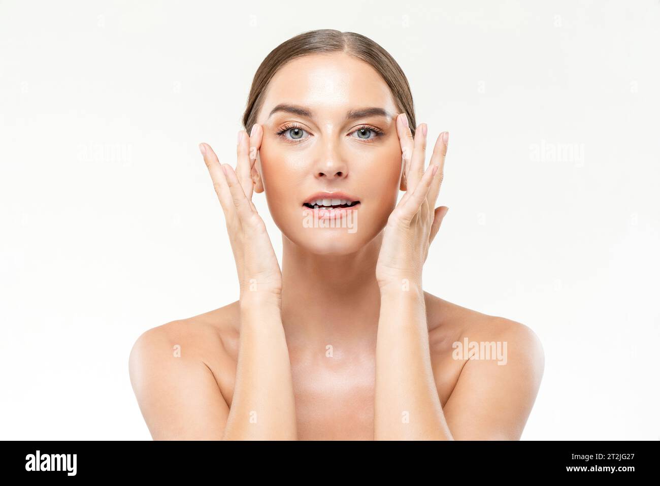 Hautpflegeportirait der schönen kaukasischen Frau, die Gesicht mit Händen auf weißem Hintergrund im Lichtstudio massiert Stockfoto