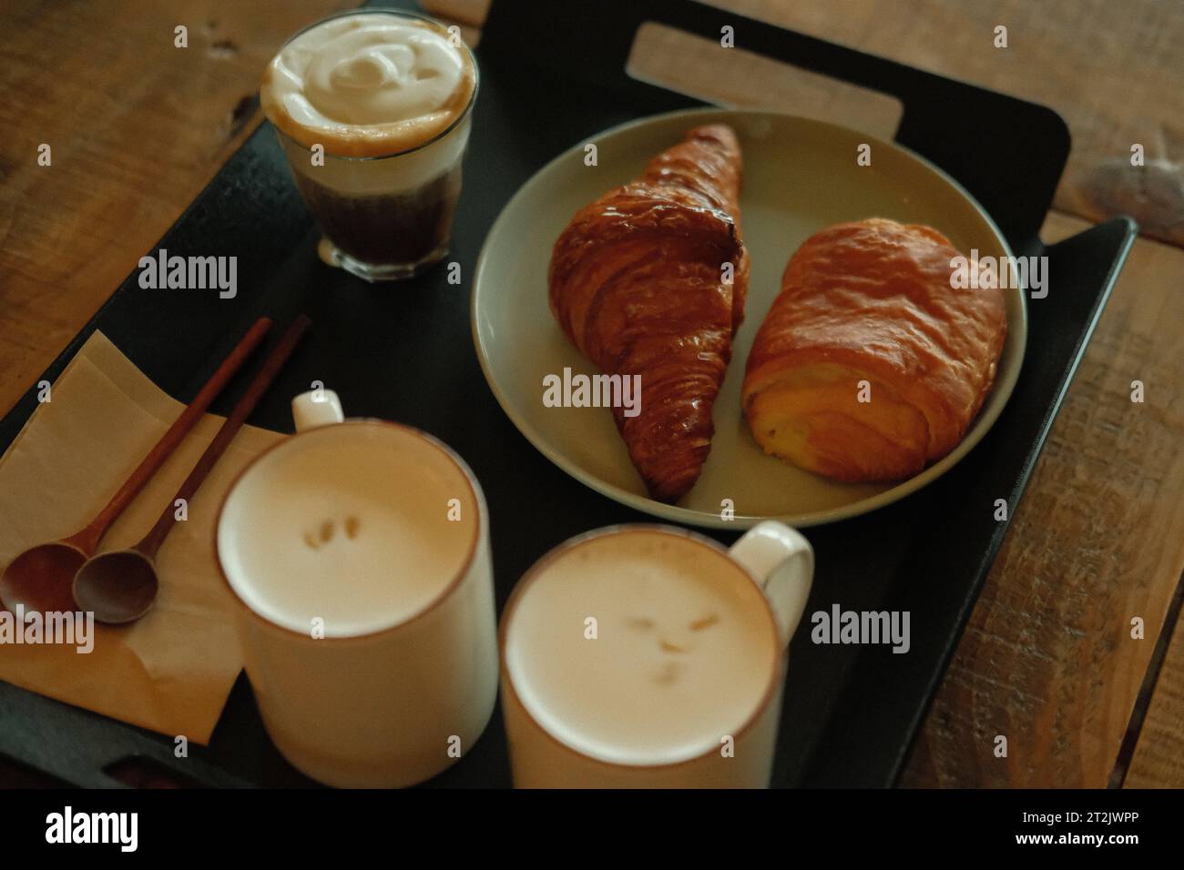 Ein köstliches Frühstück mit verschiedenen Speisen, serviert auf einem schwarzen Tablett auf einem Holztisch, mit einem Getränkeglas in der Nähe Stockfoto