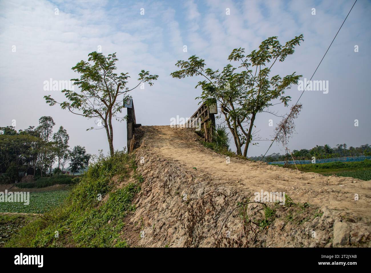 Eine schlammige Dorfstraße führt zu einem Kanal in Laxmipur, Bangladesch. Stockfoto