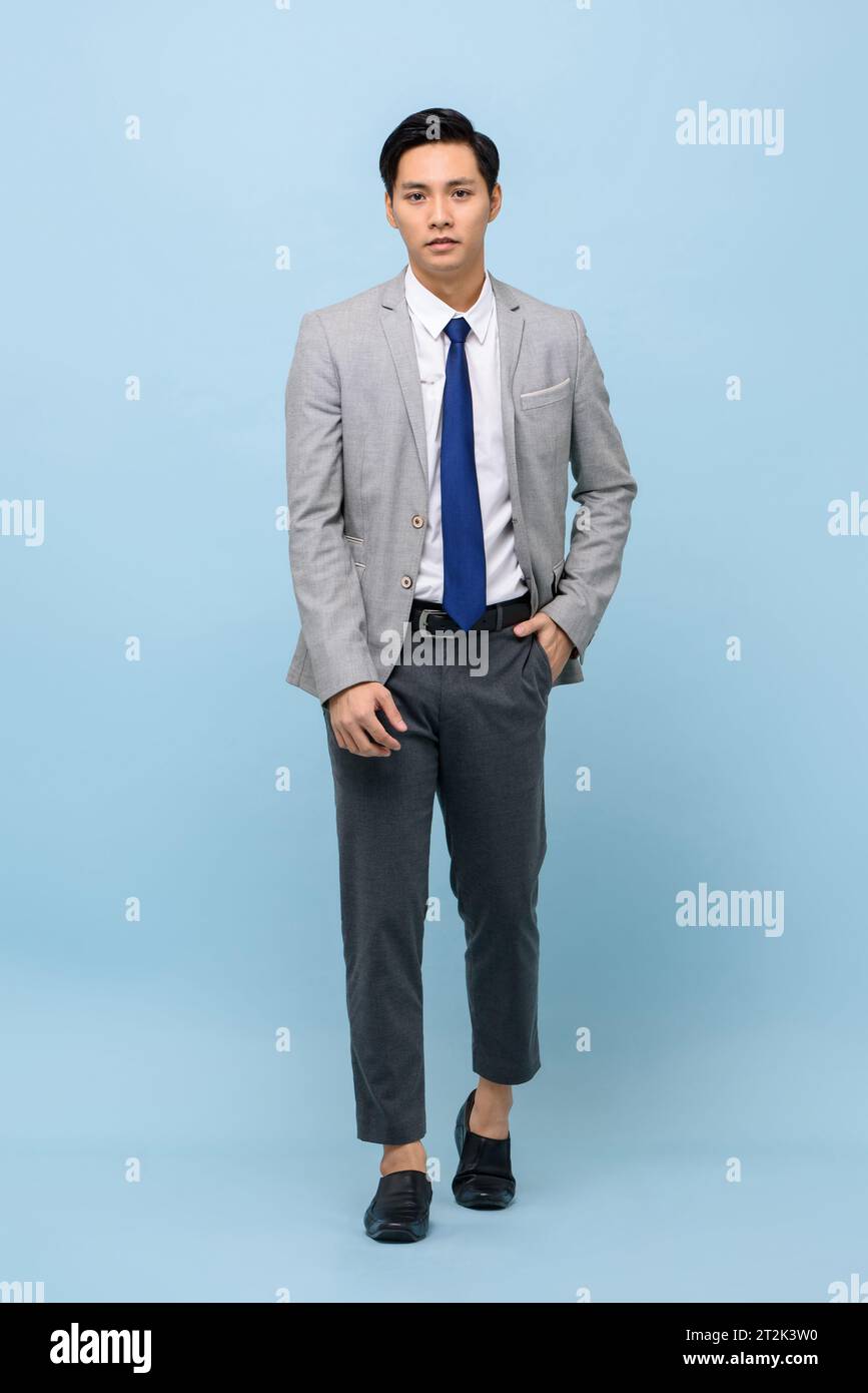 Asiatischer Mann, der Business-Anzug mit moderner Knöchelhose trägt, der im hellblauen Studio-isolierten Hintergrund läuft Stockfoto