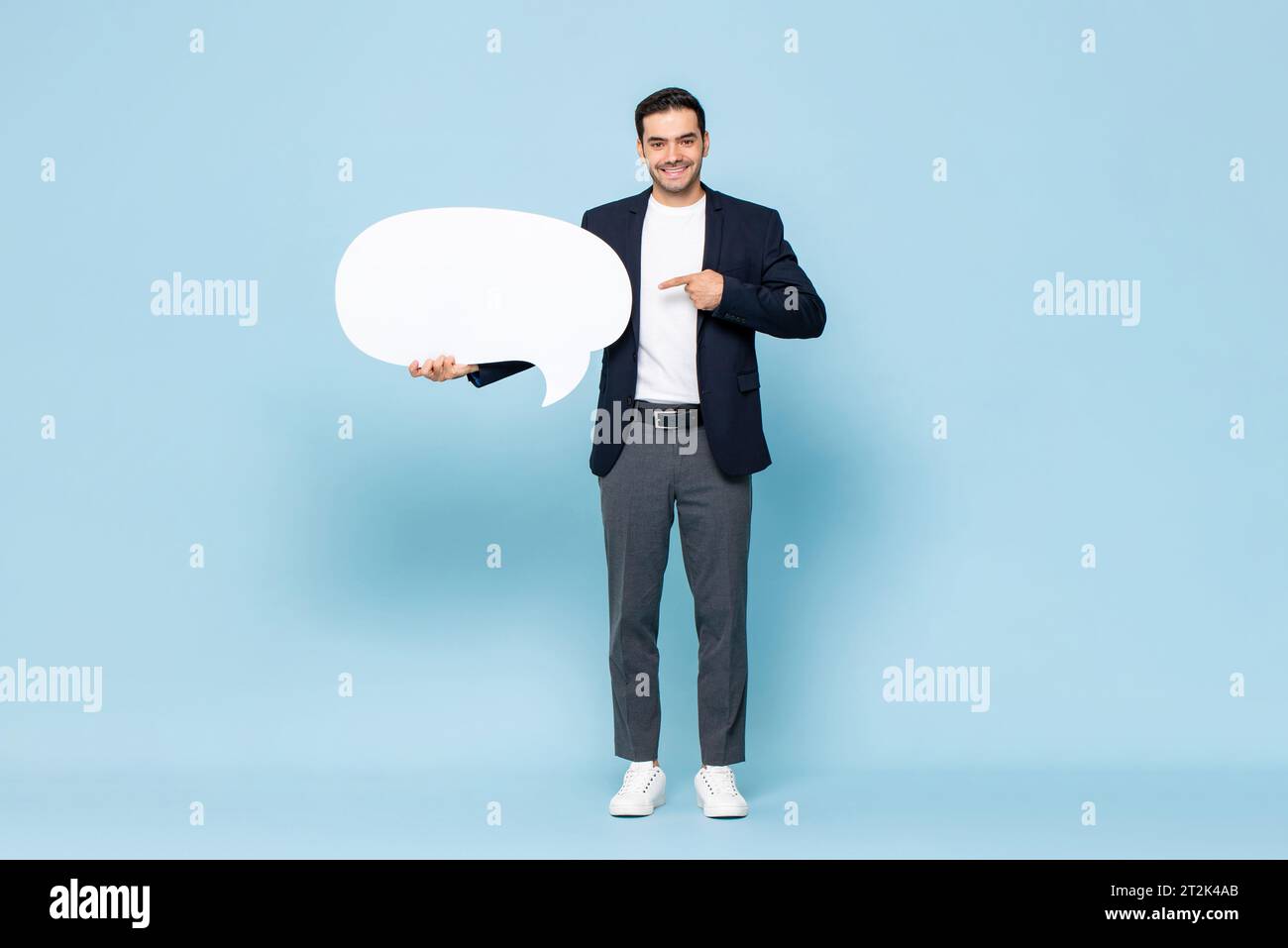 Porträt eines jungen gutaussehenden kaukasischen Mannes in formeller Kleidung, der Sprechblase auf isoliertem hellblauem Atelierhintergrund hält Stockfoto