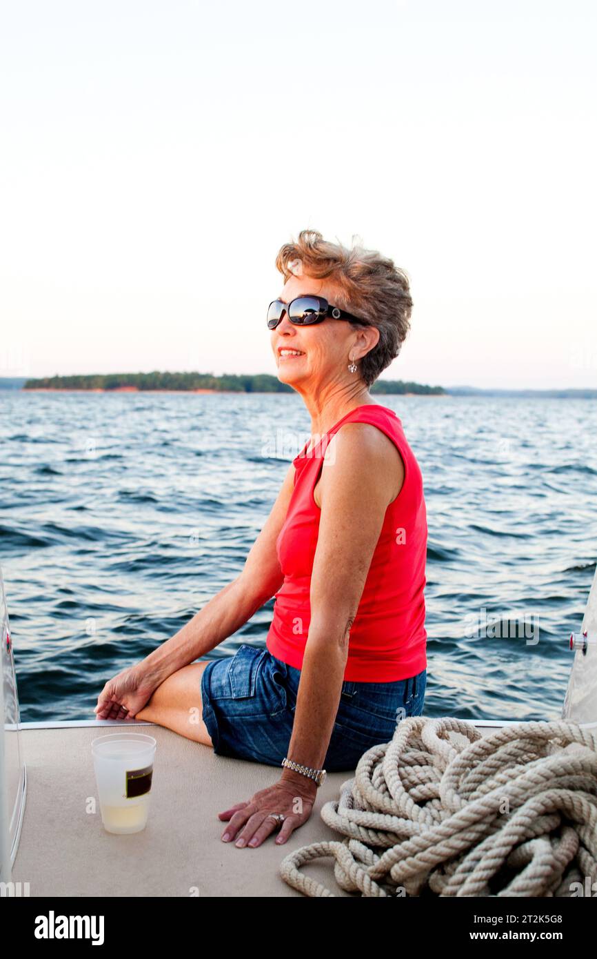 Eine Frau lächelt, während sie an einem sonnigen Abend ihre Zehen in das Wasser eines südlichen Sees taucht. Stockfoto