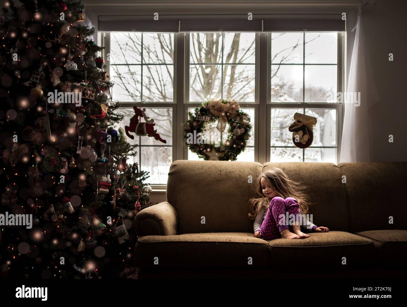 Ein junges Mädchen lächelt und sieht im Winter den weihnachtsbaum an Stockfoto