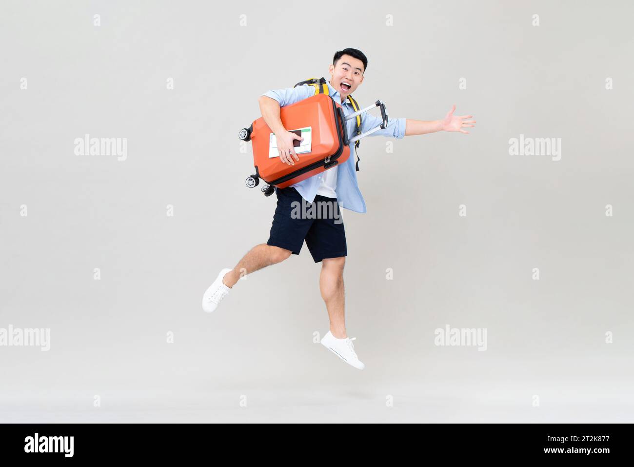 Staunender junger asiatischer Touristen, der springt, während er Koffer, Bordkarte und Reisepass in der Hand hält, Studio-Aufnahme isoliert in grauem Hintergrund Stockfoto Staunender junger asiatischer Touristen, der springt, während er Koffer, Bordkarte und Reisepass in der Hand hält, Studio-Aufnahme isoliert in grauem Hintergrund Stockfoto