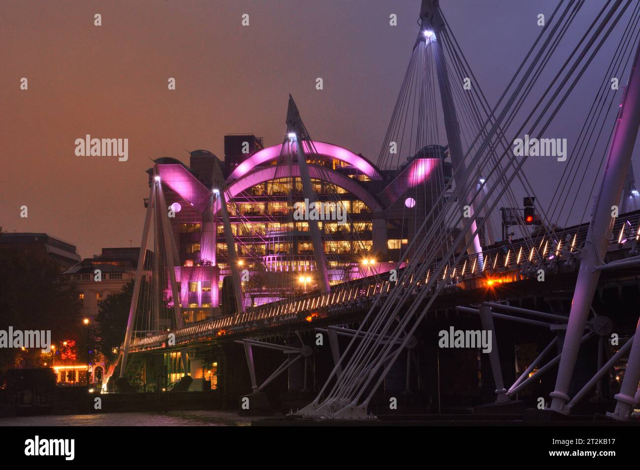 Golden Jubilee Bridge und Charing Cross Bahnhof beleuchtet mit rosafarbenen Lichtern Stockfoto