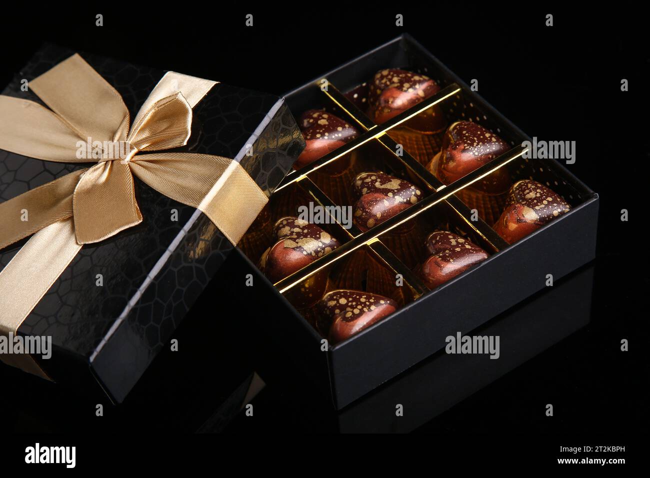 Herzförmige bemalte Luxus handgemachte Bonbons in einer Geschenkbox auf schwarzem Hintergrund. Schokolade zum Valentinstag. Stockfoto