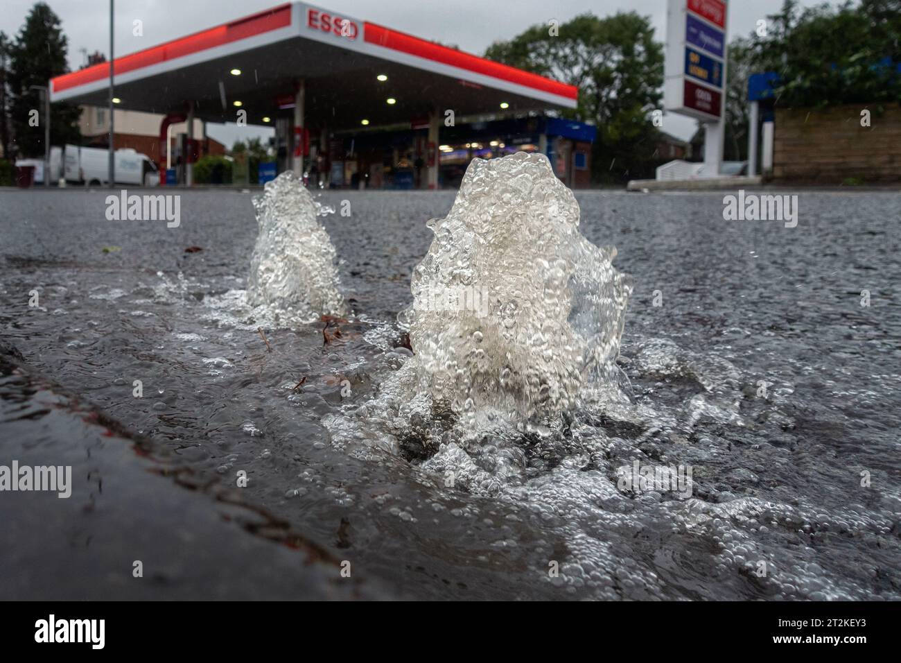 Wetter in Großbritannien - 20. Oktober 2023 - Hochwasser sprudelt durch einen Sturmabfluss auf der A65 bei Burley-in-Wharfedale, während der nahe gelegene Wasserspiegel des River Wharfe in Storm Babet, Burley-in-Wharfedale, Ilkley, West Yorkshire, England, rasch steigt. UK. Rebecca Cole/Alamy Live News Stockfoto