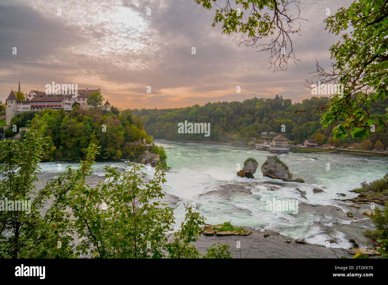 Blick auf den Sonnenuntergang über den Rheinfall, das Südufer und das Schloss Laufen hoch auf dem Hügel. Rheinfall, Europas größte Wasserfälle in der Ostschweiz. Stockfoto