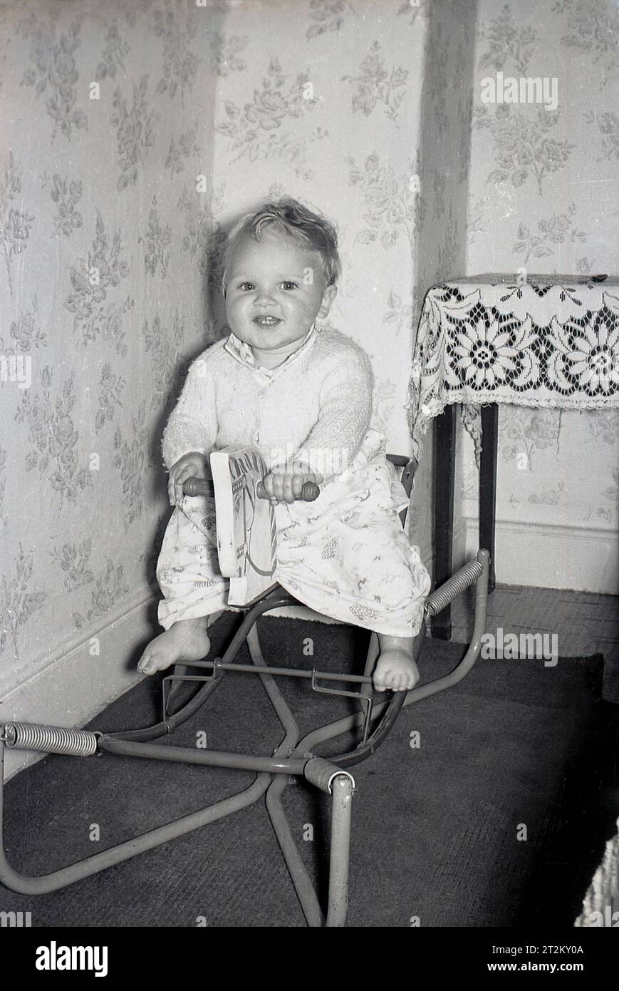 1960er Jahre Historisch, in einem Raum, ein zwitschernder Junge, der auf einem metallgerahmten, federgerahmten Schaukelpferd sitzt, England, Großbritannien. Stockfoto