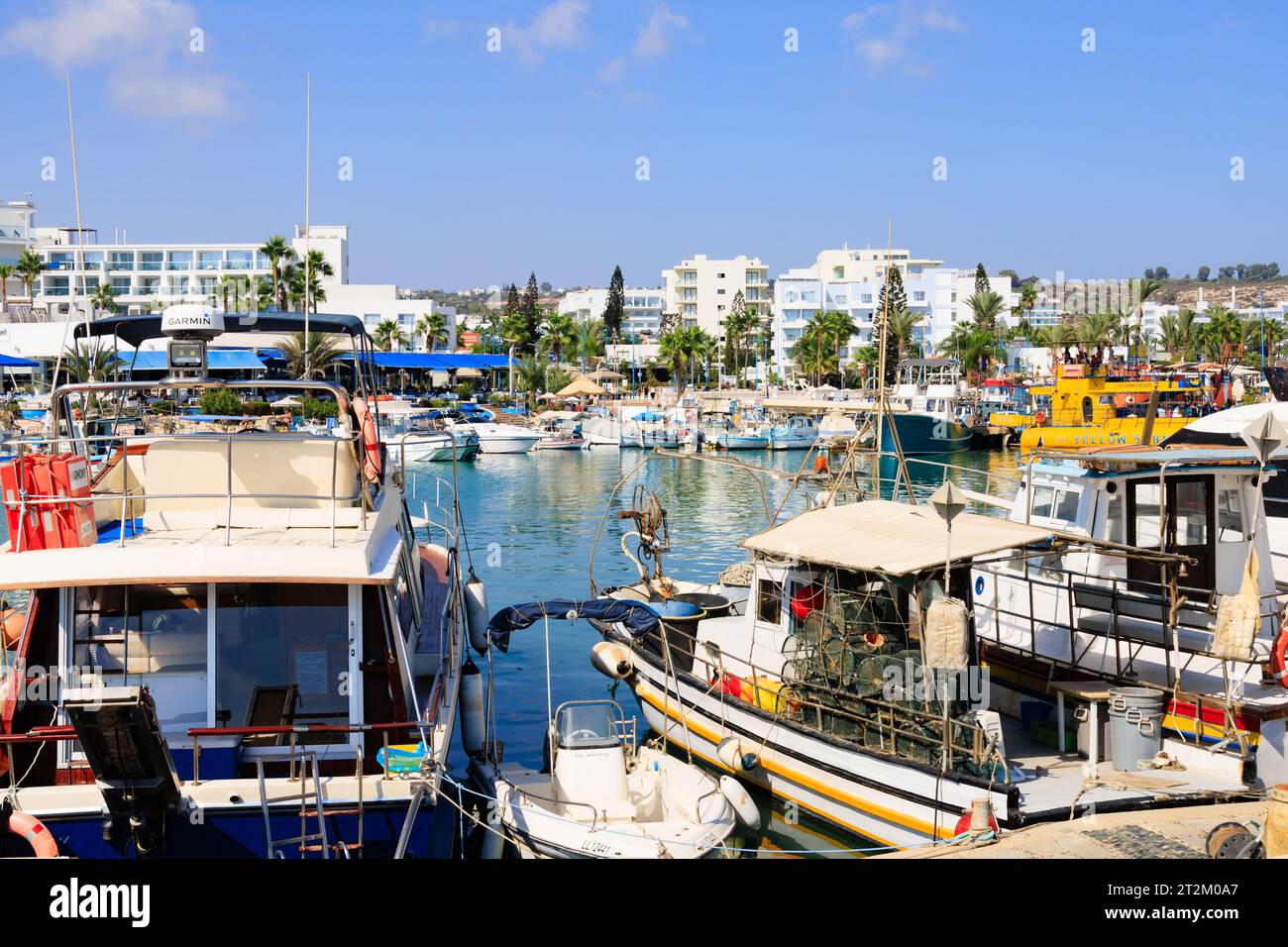Traditionelles zypriotisches Fischerboot, das neben touristischen Vergnügungsbooten im Hafen von Ayia Napa vor Anker liegt. Touristenhotels im Hintergrund. Zypern Stockfoto