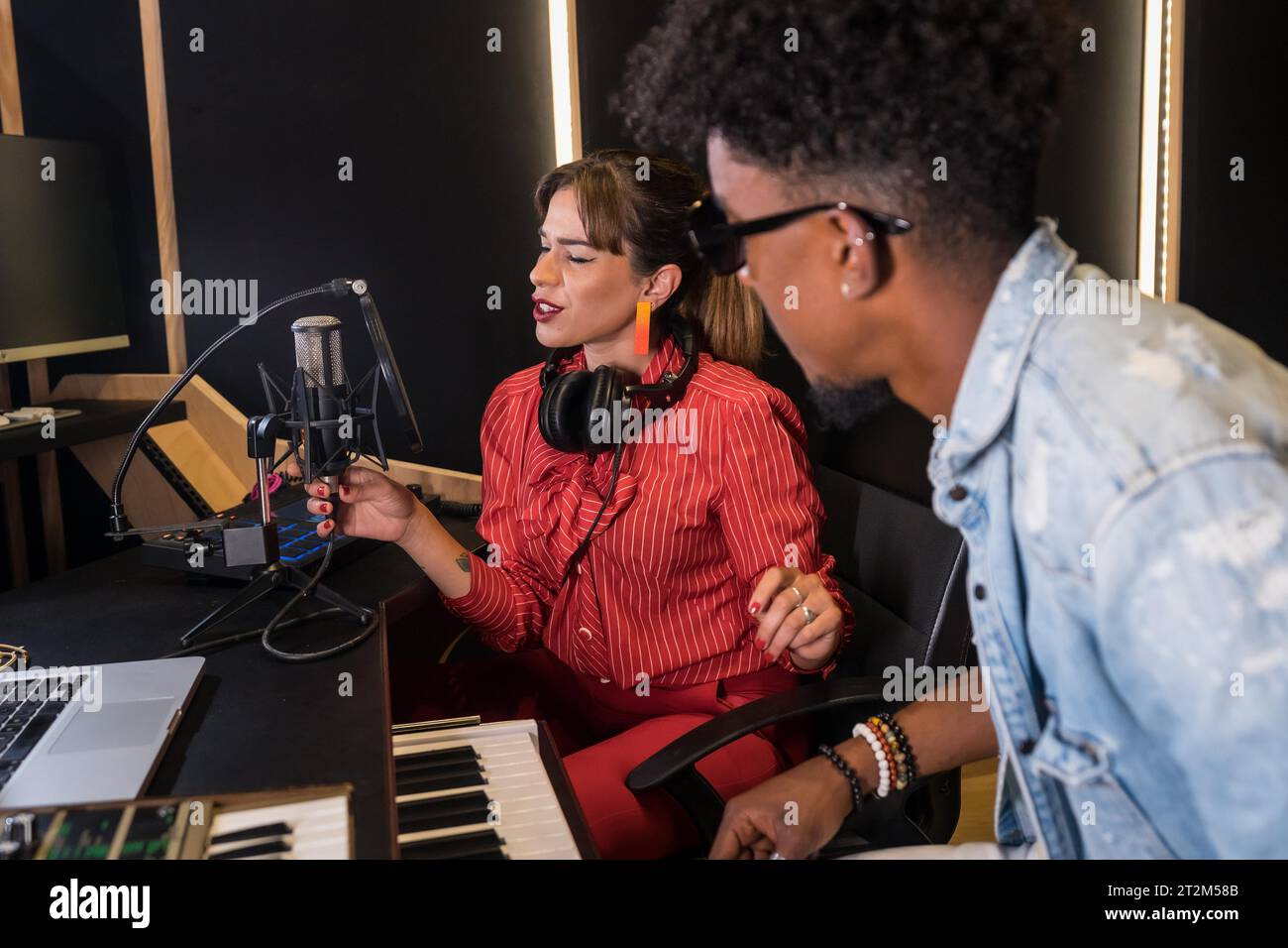 Weibliche kaukasische Sängerin und schwarze Pianistin nimmt ein neues Album im Studio auf Stockfoto