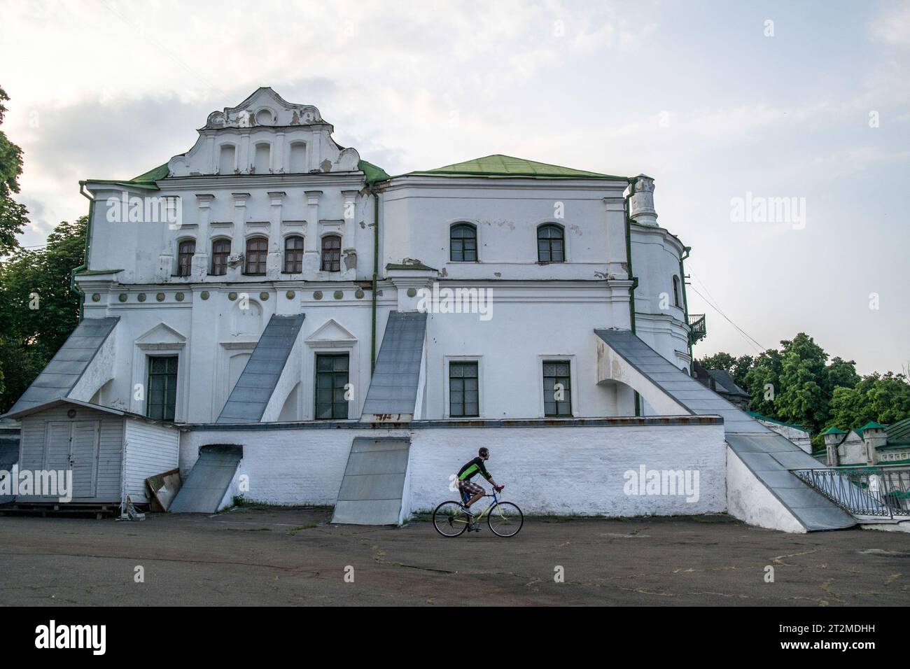 Ein Radfahrer kommt an einem der vielen Gebäude vorbei, die ein architektonisches Ensemble des Kiewer Petscherskklosters in Kiew, Ukraine, bilden Stockfoto