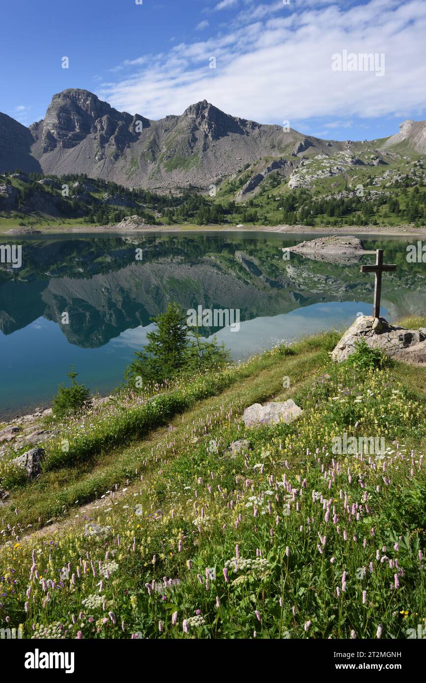 Reflexionen auf der Oberfläche des Allos-Sees oder des Lac Allos & Holzkreuzes im Nationalpark Mercantour & Haut Verdon Alpes-de-Haute-Provence Französische Alpen Frankreich Stockfoto