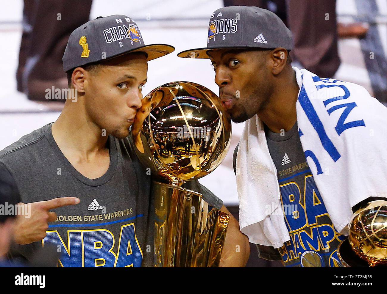 FILE - Golden State Warriors Stephen Curry, left, and Andre Iguodala kiss the Larry O'Brien Trophy after defeating the Cleveland Cavaliers 105-97 in Game 6 of basketball's NBA Finals in Cleveland, June 17, 2015. Iguodala, a four-time champion with the Golden State Warriors during a 19-year NBA career, is retiring. “It’s just the right time,” the 39-year-old Iguodala told Andscape in a telephone interview Friday, Oct. 20, 2023.(AP Photo/Paul Sancya, File) Stockfoto