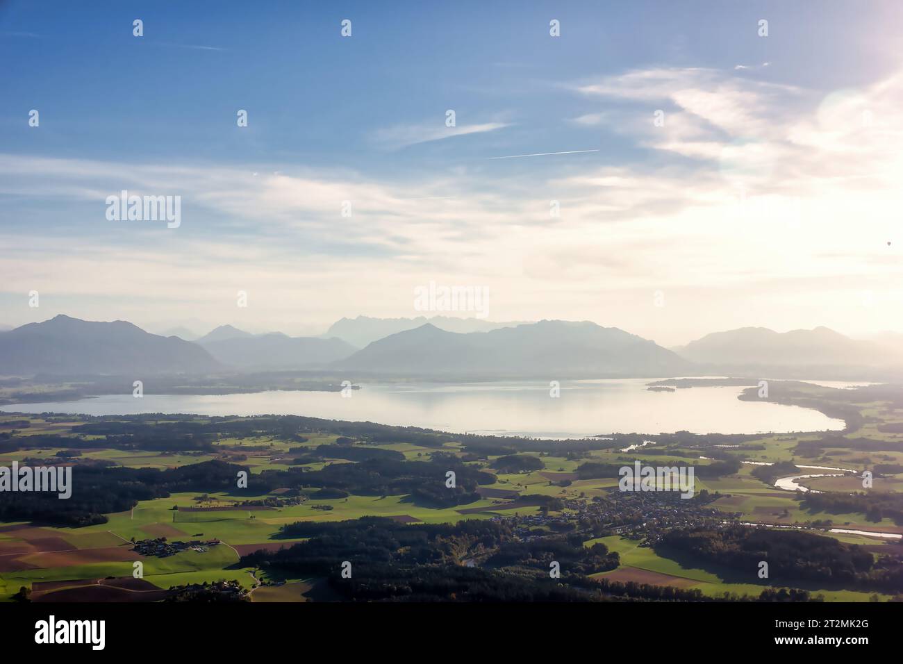 Blick über den Chiemsee auf die Alpen mit Wolken, Staub und blauem Himmel Stockfoto