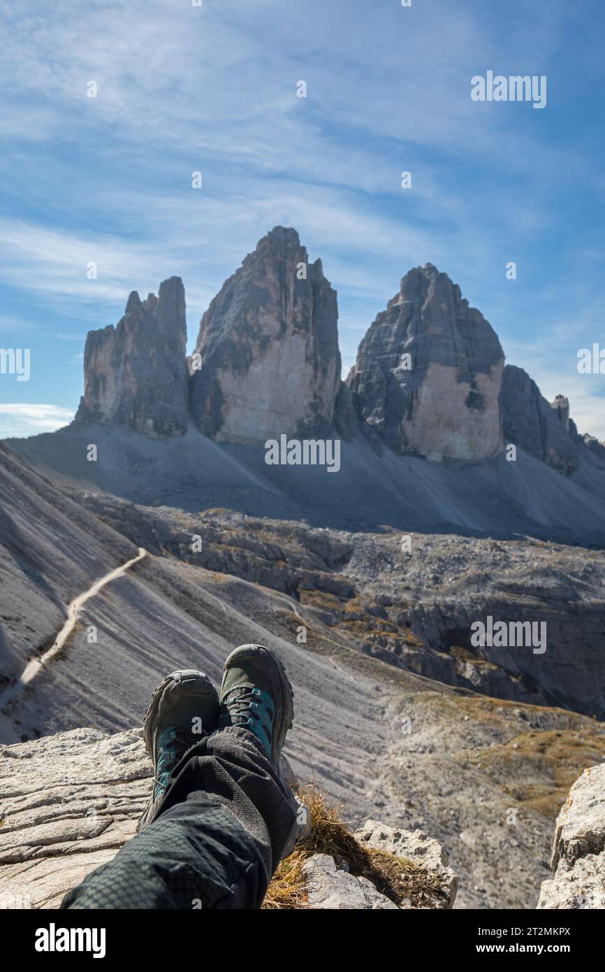 Beine eines Wanderers, der auf dem Felsen liegt und den Blick auf die berühmte drei Zinnen di Lavaredo, drei Zinnen, Dolomiten, Italien genießt Stockfoto
