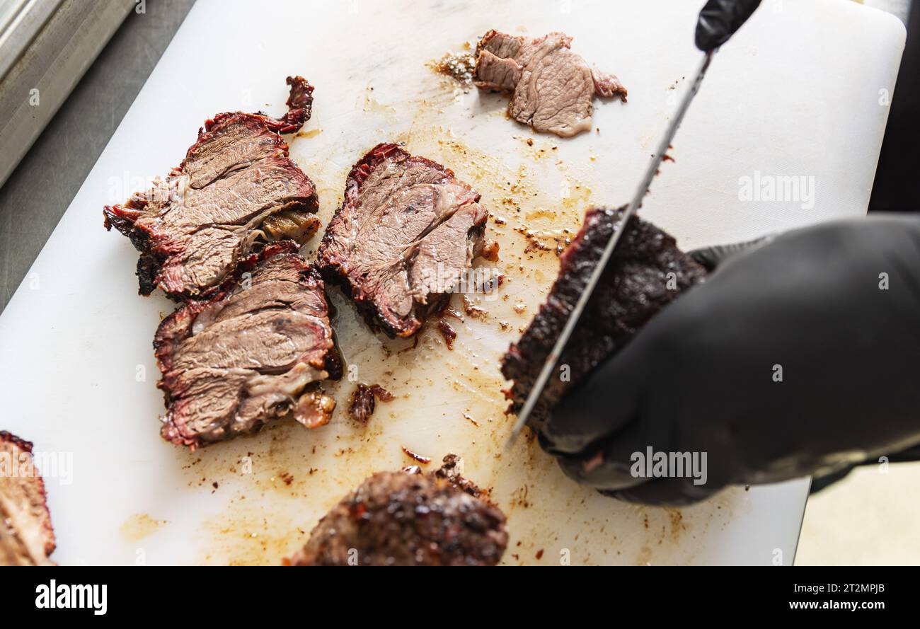 Der Koch schneidet Rindfleisch mit einem Messer. Prozesskonzept für die Lebensmittelzubereitung. Stockfoto