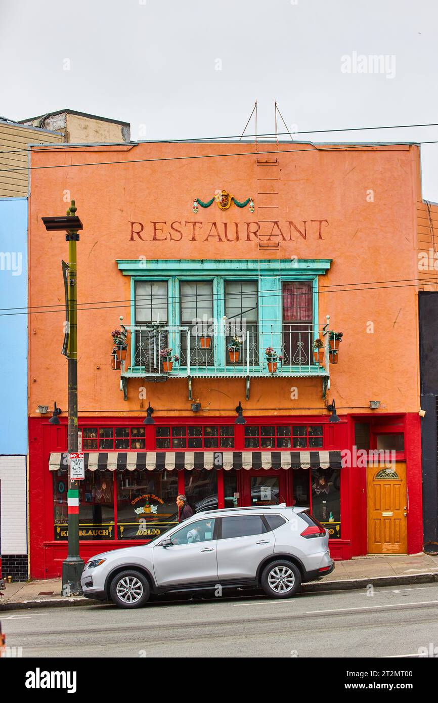 Restaurant Schild auf Gebäude mit roter Farbe unten und orange oben mit blaugrünen Erkerfenstern Stockfoto