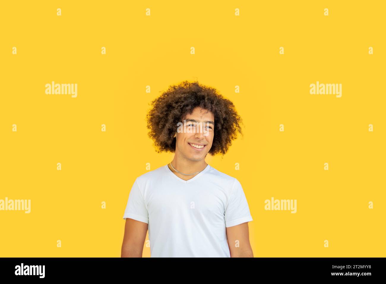Porträt eines lächelnden jungen jungen Jugendlichen gemischten Rassen-Jugendlichen der afro-italienischen Generation Z mit dicken lockigen Haaren auf gelbem Hintergrund. Glückliche multiethnische Jugendliche Stockfoto