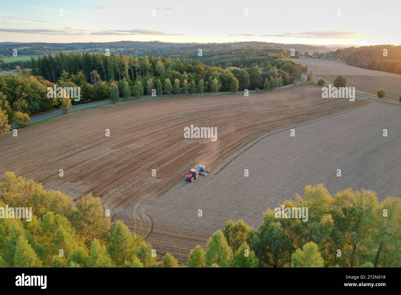 Landwirt mit Traktorsaat und Aussaat von Getreide auf dem landwirtschaftlichen Feld. Pflanzen, Weizen. Boden lockert sich auf einem Feld mit landwirtschaftlichen Nutzpflanzen, Luftaufnahme. Trac Stockfoto