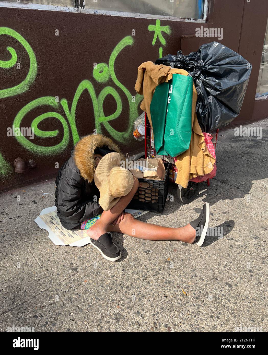 Obdachlose Frau mit Wagen brach auf einem Bürgersteig in der Lower East Side, New York City, zusammen. Stockfoto