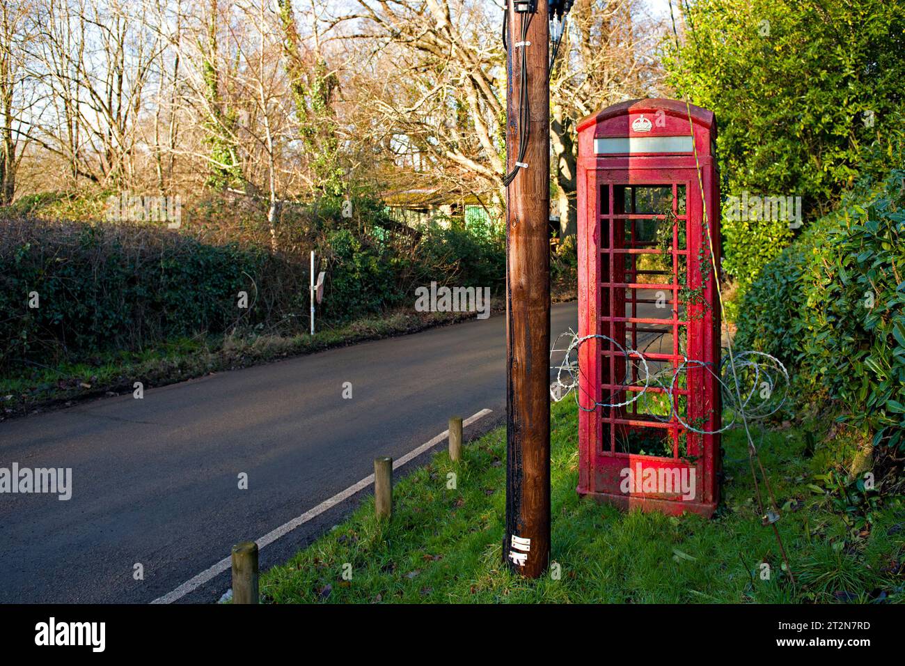 Eine außer Betrieb genommene K6-Telefonbox, umgeben von Rasierdraht auf einer Landstraße in Kent, Großbritannien Stockfoto