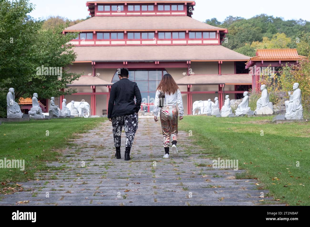 Ein chinesisch-amerikanisches Paar in moderner Kleidung nähert sich dem Eingang zum Chuang Yen Buddhist Monastery in Carmel, Putnam County, New York. Stockfoto