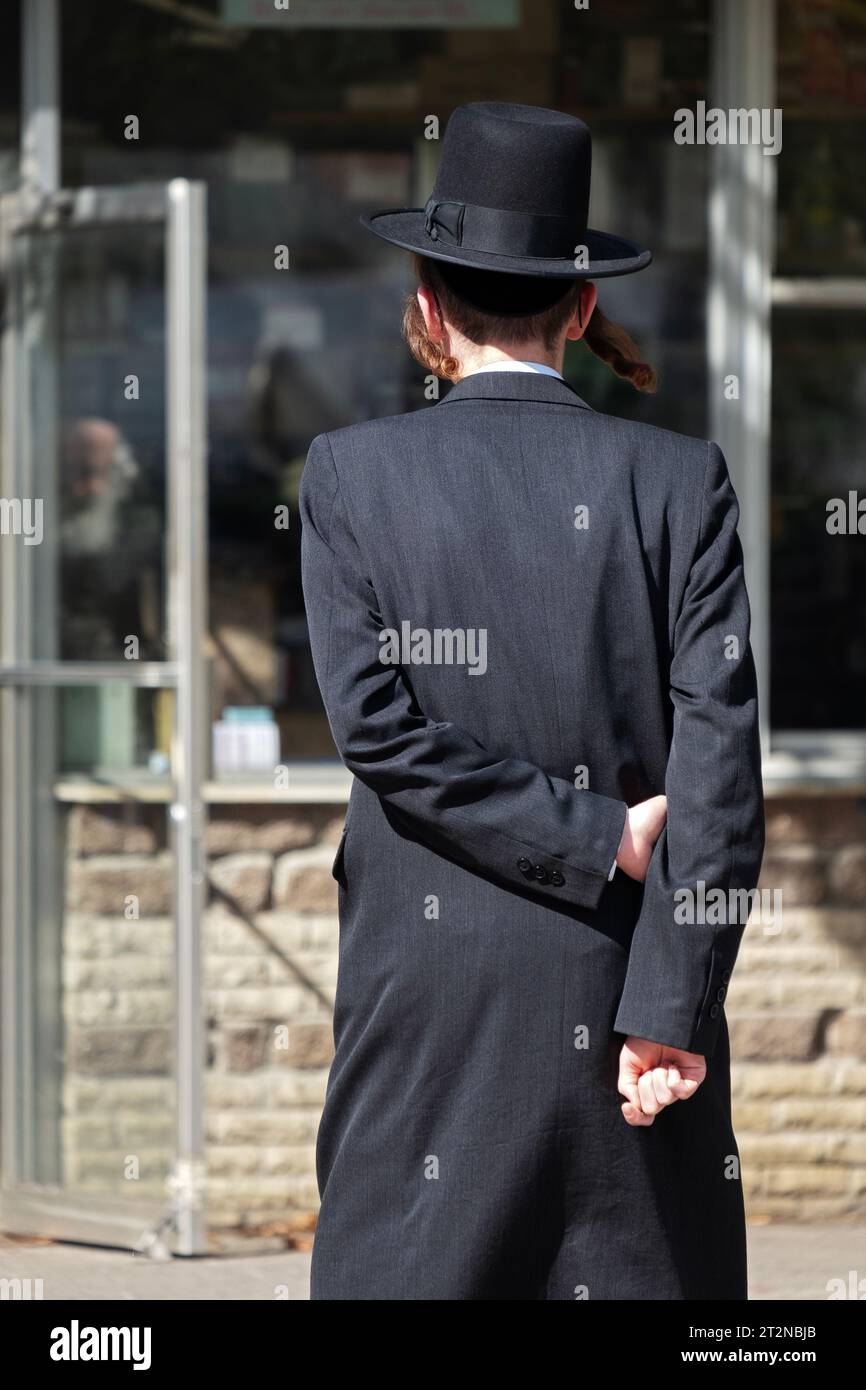 Ein nicht identifizierter orthodoxer jüdischer Mann geht mit den Armen hinter dem Rücken, eine Kommmon-Walking-Pose in jüdischen Vierteln. In Brooklyn, New York. Stockfoto