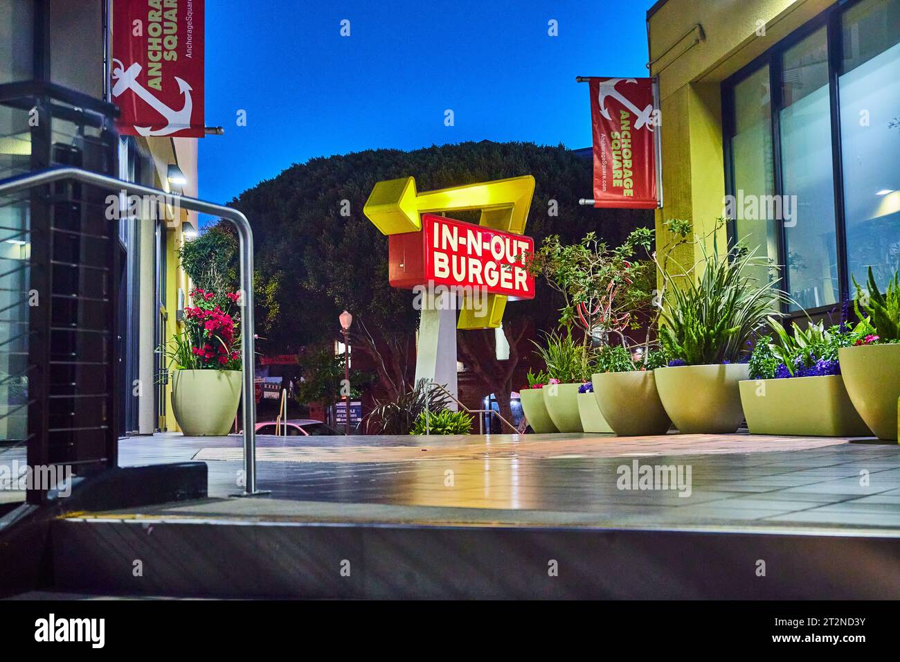 Elegante Terrasse mit Topfpflanzen und Blumen und abgelegenem in N Out Burger Schild bei Nacht Stockfoto