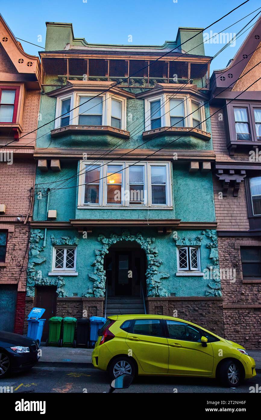 Teal-Haus mit einer Fassade, die wie eine Steinhöhle strukturiert ist, und Licht im zweiten Stock mit Erkerfenstern Stockfoto