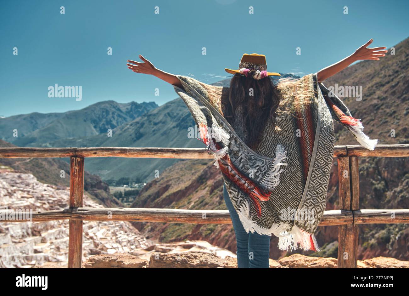 Weibliche Touristen mit in Hut und Poncho, die Maras Salzminen, Peru erkunden. Reise- und Fernweh-Konzept. Stockfoto