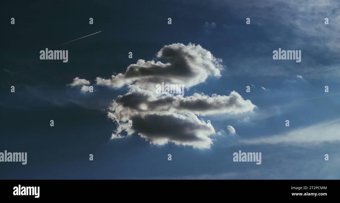 Traumhaft weiße Wolkenlandschaft unter tiefblauem Himmel und ein rasantes Jet-Flugzeug, das durch den Himmel gleitet und eine schneeweiße Kondensationsspur hinterlässt. Stockfoto Traumhaft weiße Wolkenlandschaft unter tiefblauem Himmel und ein rasantes Jet-Flugzeug, das durch den Himmel gleitet und eine schneeweiße Kondensationsspur hinterlässt. Stockfoto