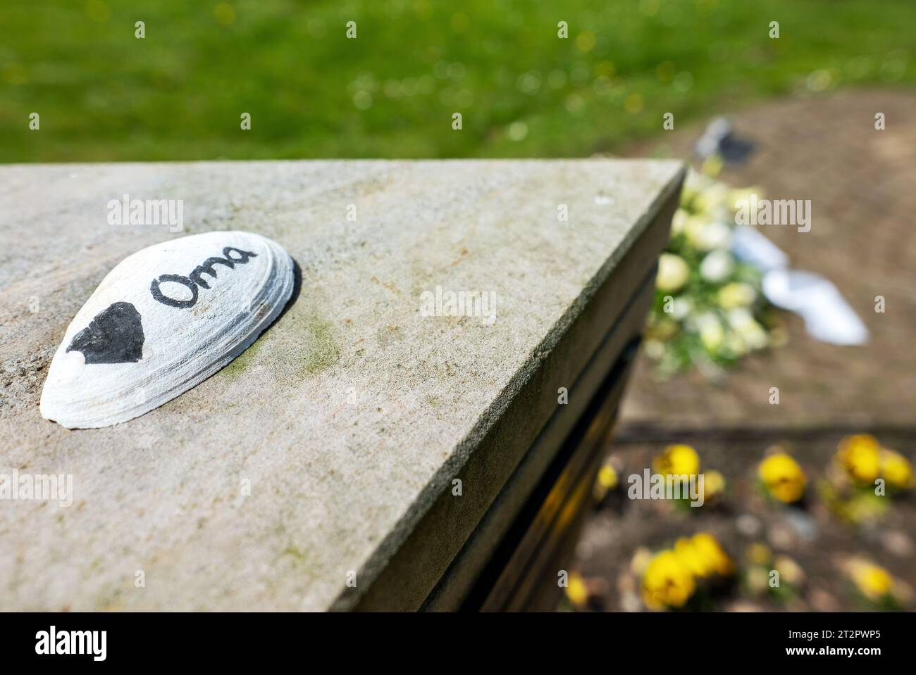 Urnengrab auf dem Friedhof mit Oma (Oma) als Abschied vom Enkelkind auf der Shell. Stockfoto