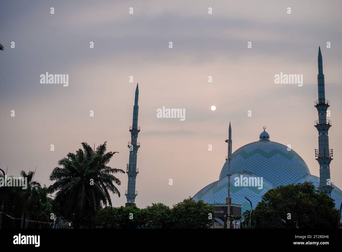 Wunderschöne Moschee mit Minaretten auf jeder Seite. Himmel Hintergrund mit der Sonne, wenn sie untergeht. Von vorne gesehen mit großem Blickwinkel Stockfoto