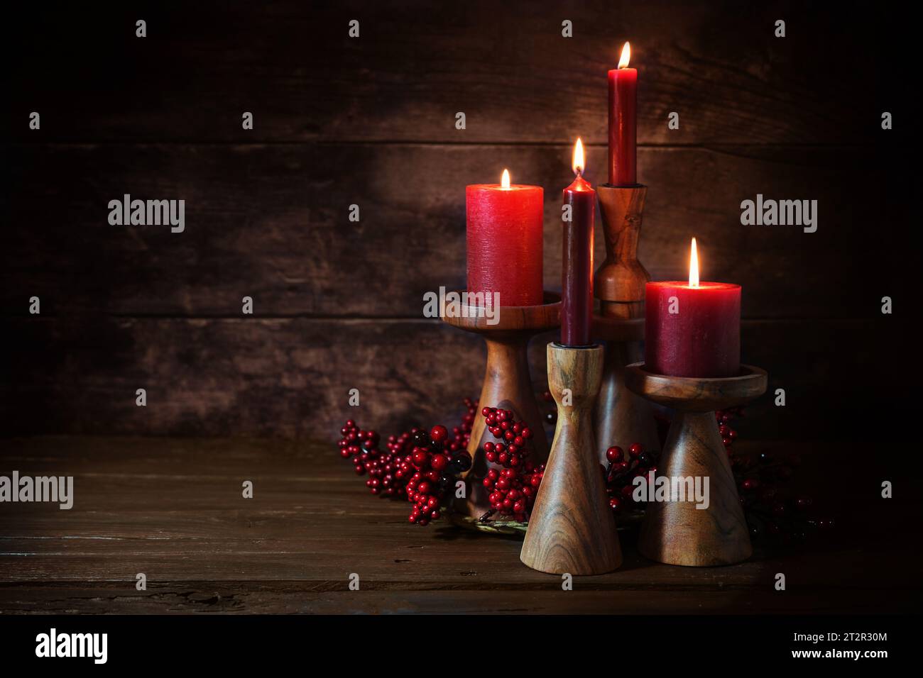 Gruppe von vier roten Kerzen in Kerzenstäben aus Holz als Adventsdekoration vor dunklem rustikalem Holzhintergrund, Ferienwohndekor, Kopierraum, Stockfoto