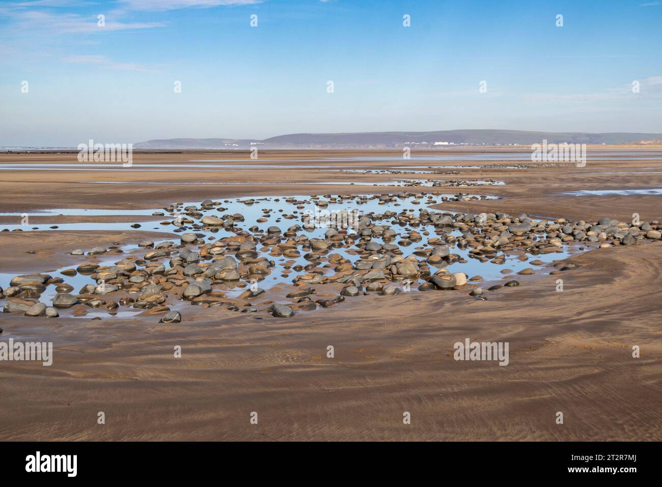 Winter, Northam Beach View mit Kieselsteinen, die von Longshore Drift getragen werden, Blick auf Taw Torridge Estuary und Saunton Sands mit blauem Himmel und Wolken. Stockfoto