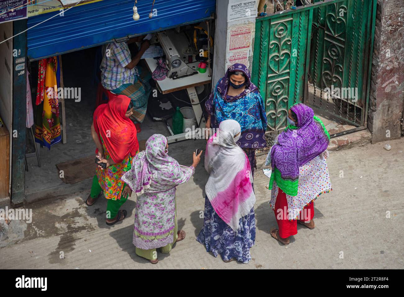 Frauen tratschen vor einem Laden während der covid 19 Pandemie-Sperrung in einer Straße in Dhaka, Bangladesch. Stockfoto