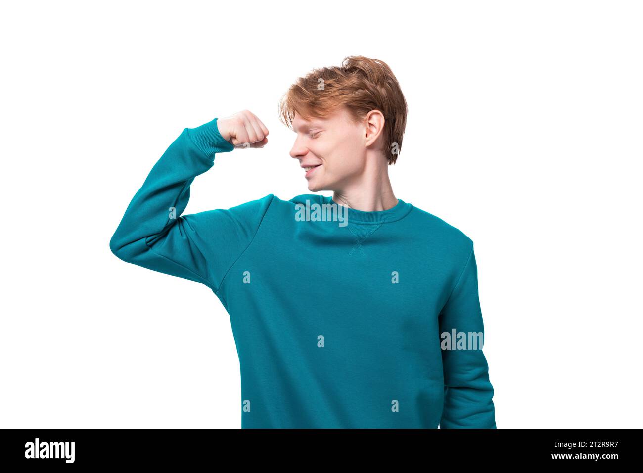 Ein junger Mann mit rotem Haar in einem blauen Pullover zeigt Stärke Stockfoto