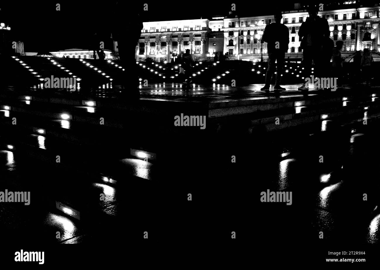 Eine dunkle Nachtstraße mit nassem Asphalt und Laternen. Schwarzweißbild Stockfoto