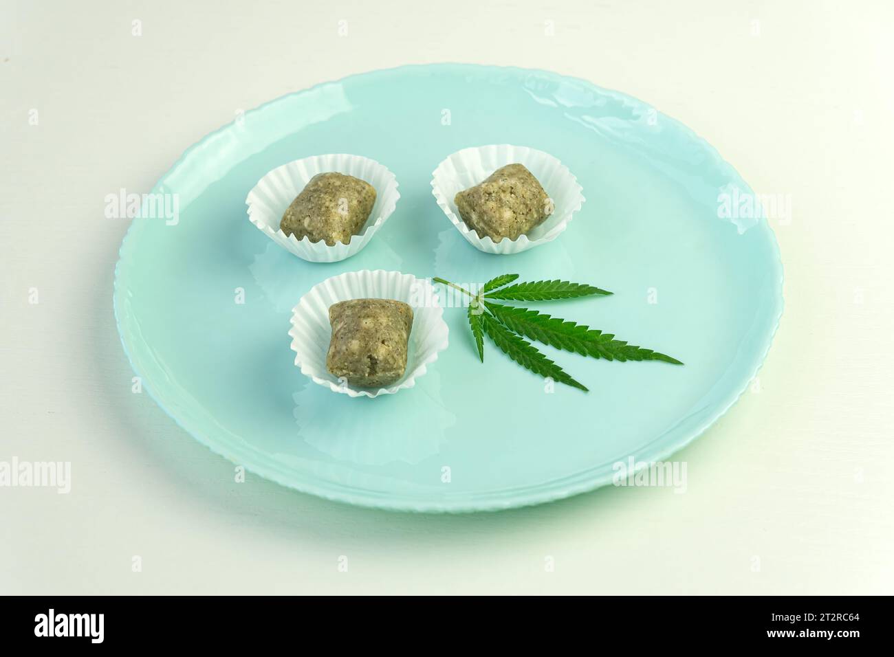 Hausgemachte Süßigkeiten mit Hanfsamen und Datteln. Gesundes veganes Essen auf dem blauen Tisch. Ein Betäubungsmittel. Legalisation von leichten Medikamenten Stockfoto