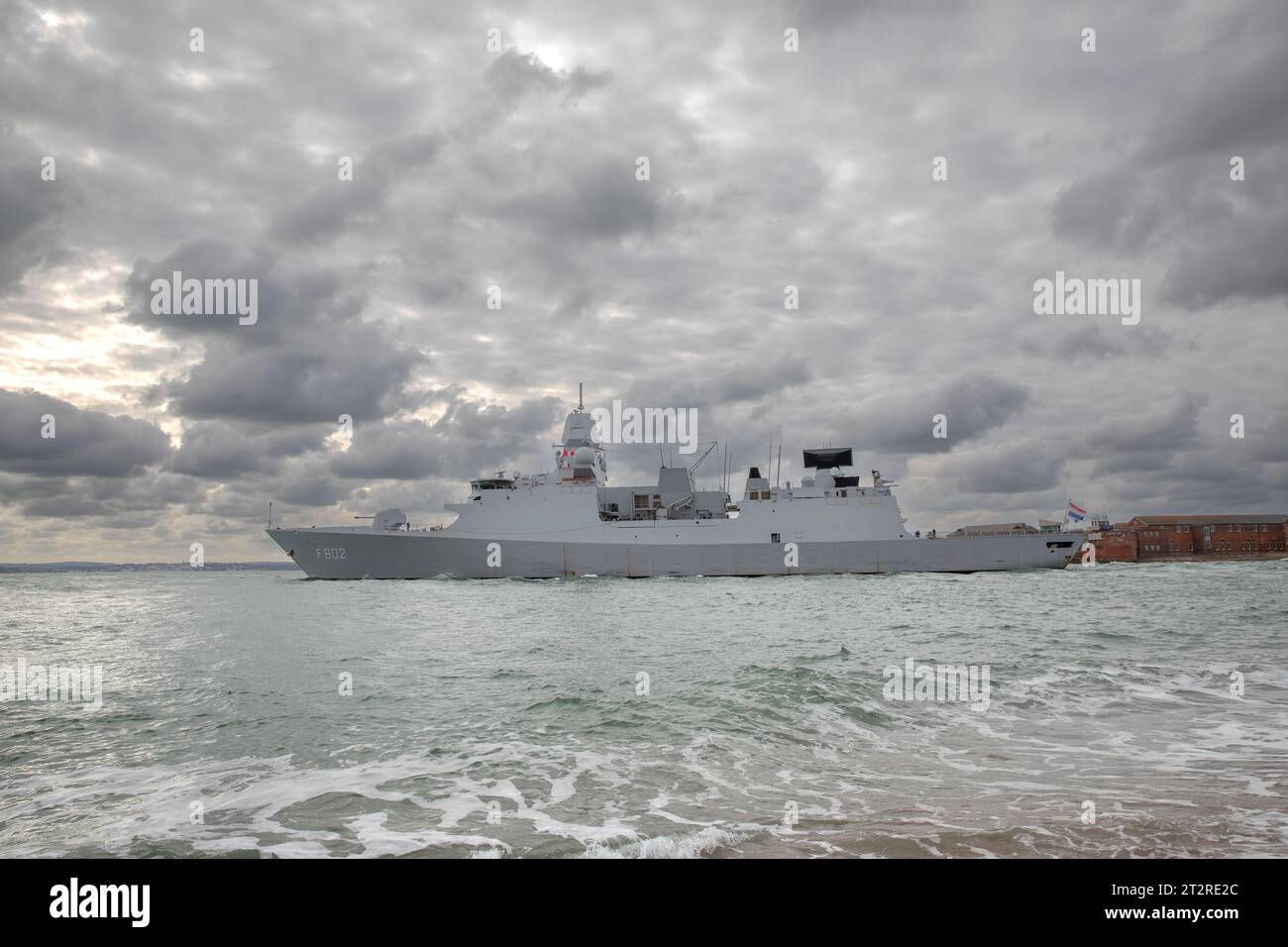 Die niederländische F802 HNLMS de Seven Provincien verlässt den Hafen von Portsmouth. Dunkler Himmel über uns. Niedriger Winkel, quadratisch zur Anschlussseite. Stockfoto
