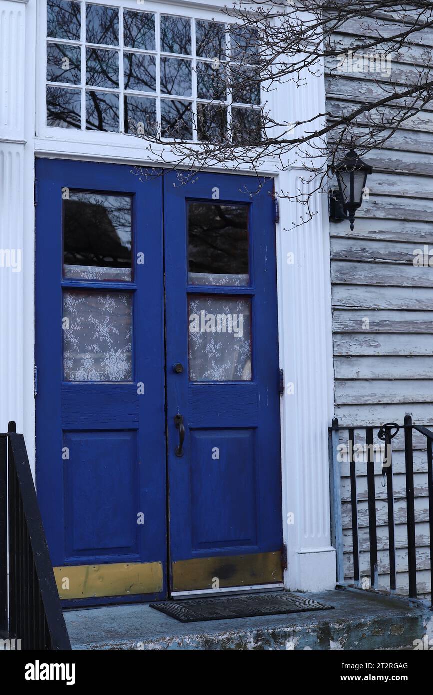Blaue Doppeltüren und weiße Spitzenvorhänge Stockfoto