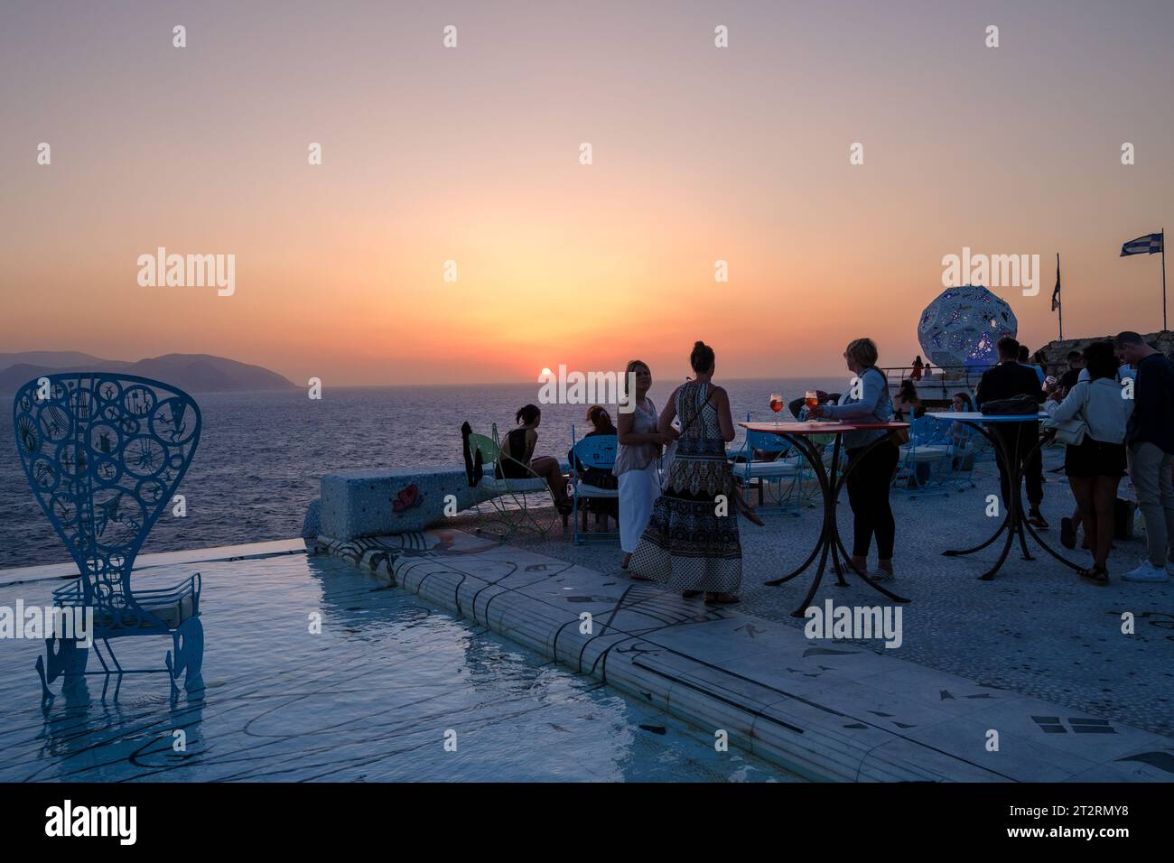 IOS, Griechenland - 11. September 2023 : Junge Menschen treffen sich an einem Pool in einer Lounge Bar, um den Sonnenuntergang in iOS kykladen Griechenland zu beobachten Stockfoto
