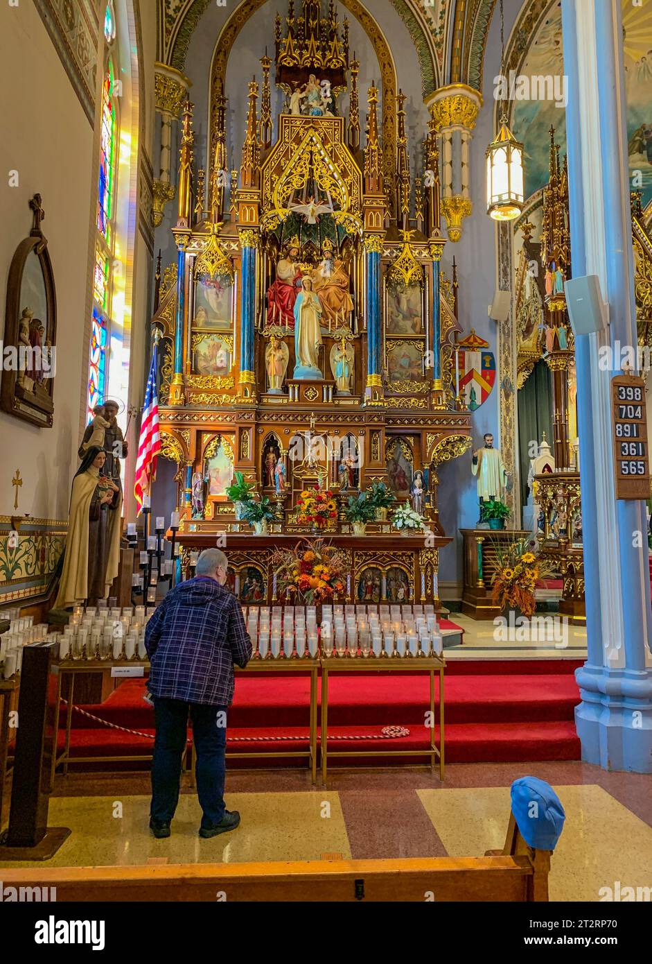 Dyersville, Iowa, USA. St. Franziskus Xavier Basilika, Altar der Gottesmutter, errichtet 1897. Der Anbeter bereitet sich vor, eine Kerze anzuzünden. Nach links o Stockfoto