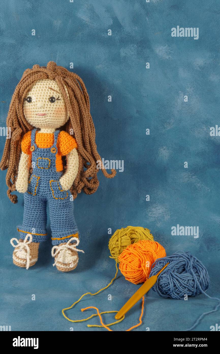 Amigurumi Puppe handgefertigt auf blauem Hintergrund mit den Garnen, die für ihre Herstellung verwendet wurden Stockfoto